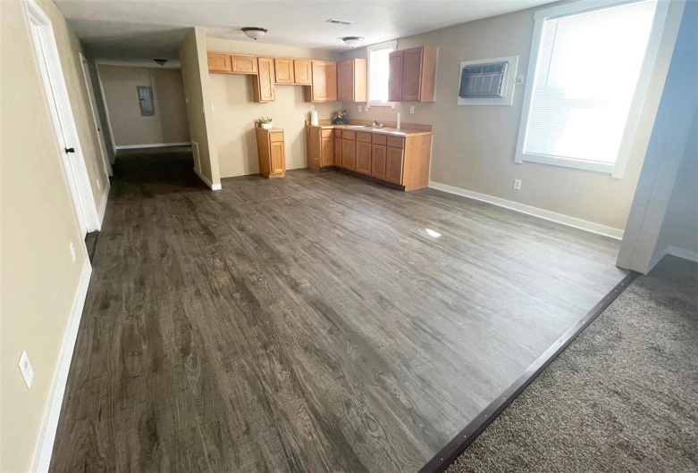 Kitchen with a wall mounted AC, dark wood-style flooring, baseboards, visible vents, and a sink