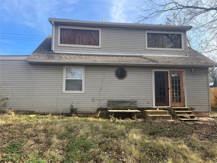 Back of property with a shingled roof and entry steps