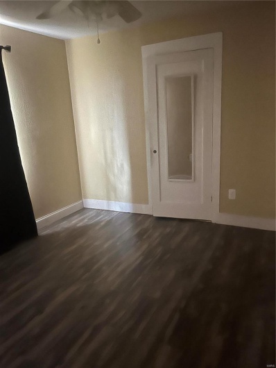 Spare room with baseboards, dark wood-type flooring, and a ceiling fan