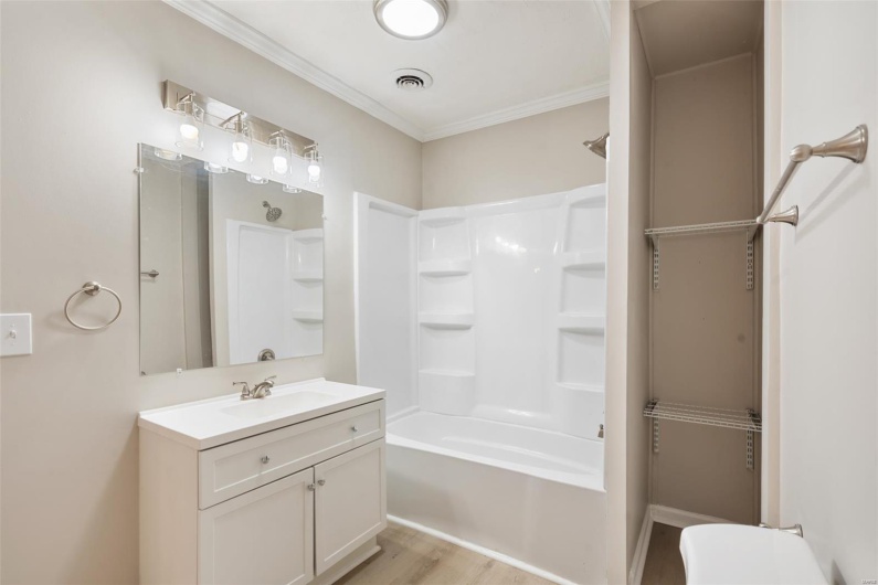 Bathroom with visible vents, ornamental molding, wood finished floors, vanity, and shower / bathtub combination