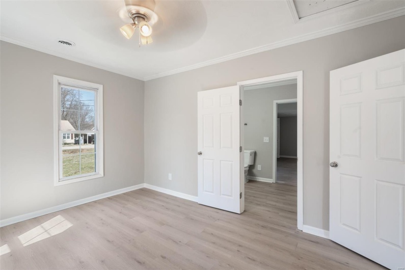 Unfurnished bedroom with crown molding, a ceiling fan, light wood-type flooring, baseboards, and visible vents