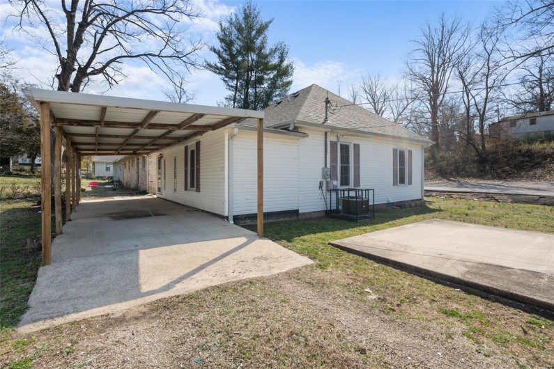 View of home's exterior with concrete driveway, roof with shingles, and a carport