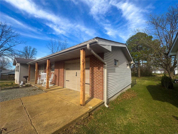 View of home's exterior with brick siding, concrete driveway, a garage, and a yard