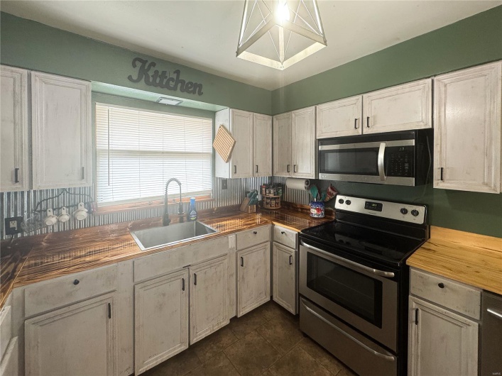 Kitchen featuring white cabinetry, a sink, appliances with stainless steel finishes, and butcher block counters