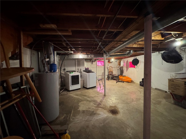 Unfinished basement featuring washing machine and clothes dryer and gas water heater