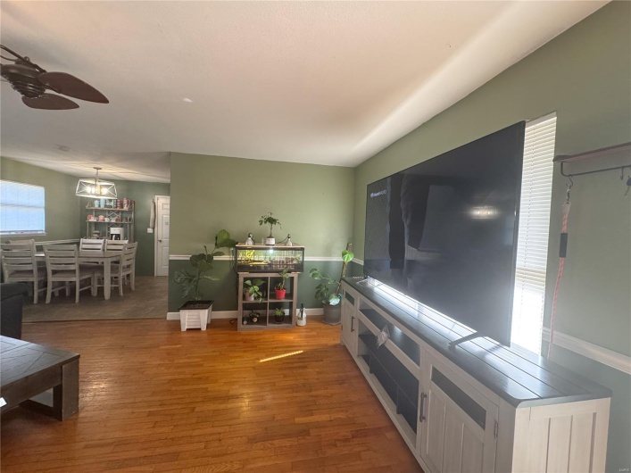 Living room with baseboards, ceiling fan, wood finished floors, and a healthy amount of sunlight