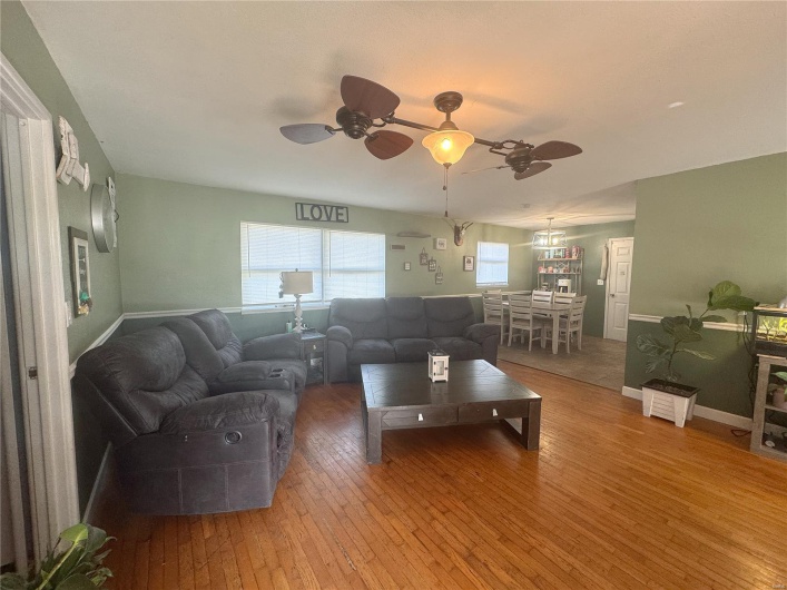 Living area with baseboards, hardwood / wood-style flooring, and a ceiling fan