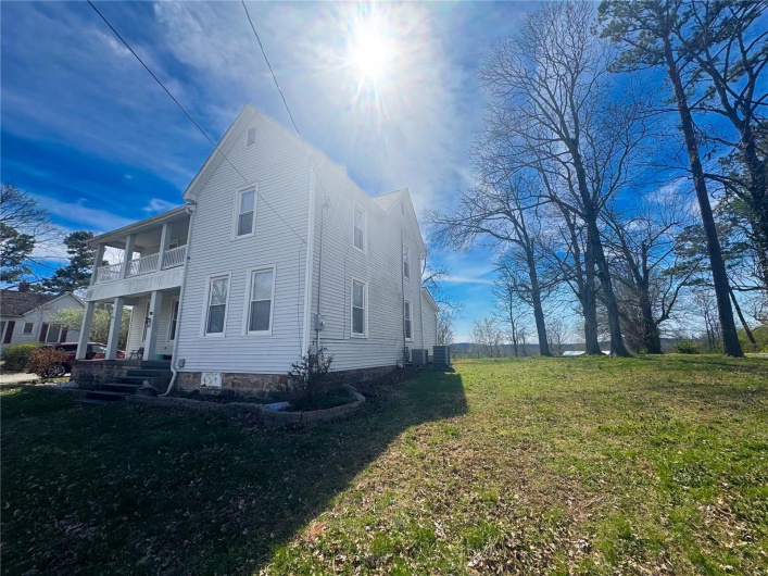 View of side of home with a balcony, central AC unit, and a yard