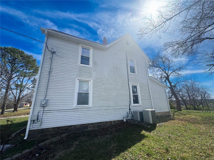 View of side of home with a lawn and cooling unit