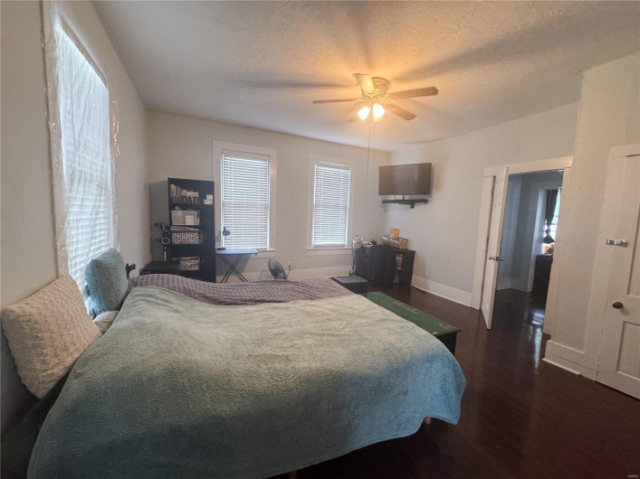 Bedroom with dark wood-style flooring, baseboards, ceiling fan, and a textured ceiling