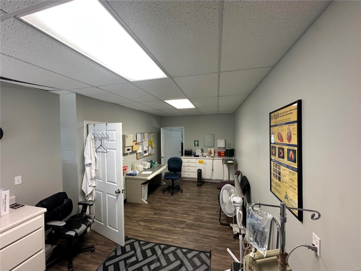 Office with a paneled ceiling and dark wood-style flooring