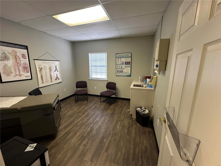 Office area with a sink, baseboards, a paneled ceiling, and dark wood-style floors