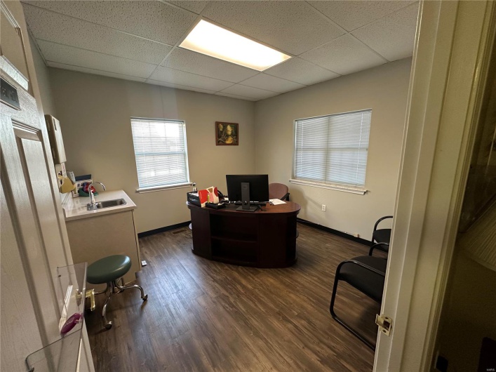 Office with a sink, a paneled ceiling, baseboards, and dark wood-style flooring