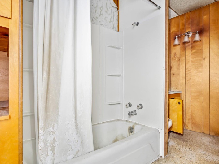 Bathroom featuring wooden walls and shower / tub combo