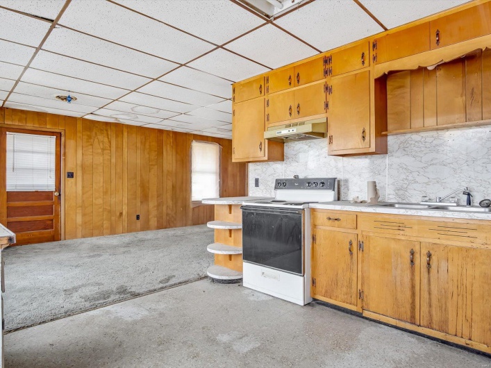 Kitchen with a paneled ceiling, range with electric cooktop, sink, and wood walls