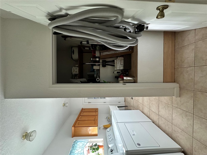 Washroom featuring washing machine and clothes dryer, a textured ceiling, baseboards, cabinet space, and light tile patterned floors