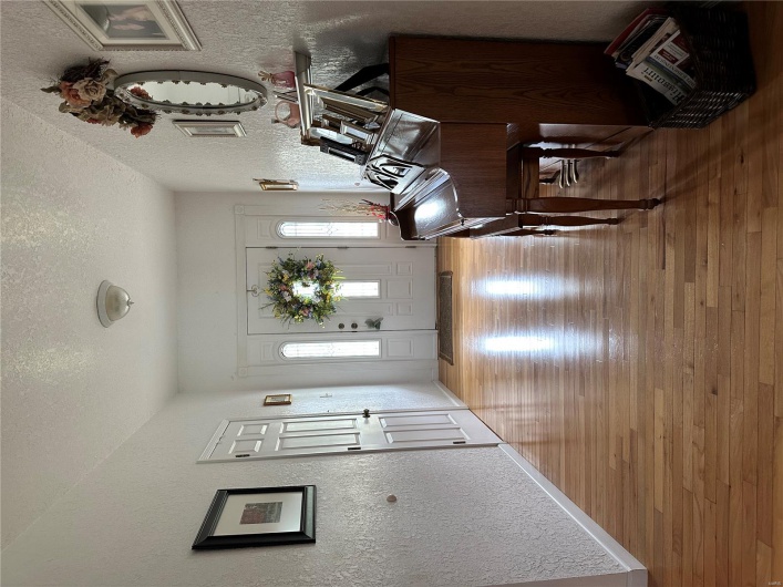 Entryway featuring a textured wall, hardwood / wood-style flooring, baseboards, and a textured ceiling
