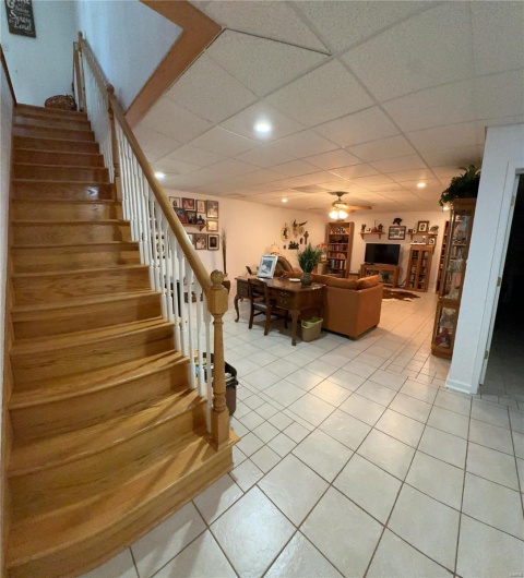 Stairway with a drop ceiling, tile patterned flooring, and a ceiling fan