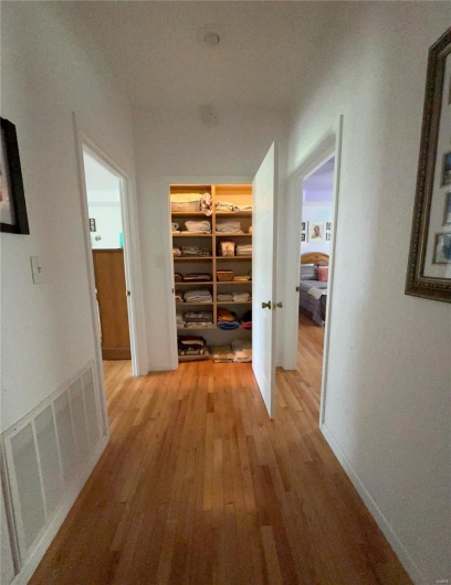 Corridor with hardwood flooring, baseboards, and visible vents