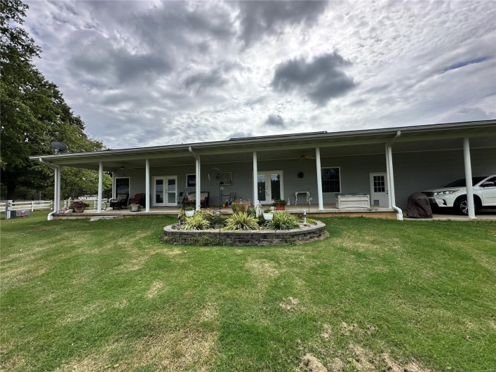 Back of property with an attached carport, a patio, french doors, and a yard