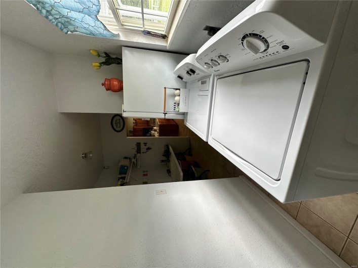 Laundry area with washing machine and clothes dryer, a textured ceiling, baseboards, laundry area, and light tile patterned floors