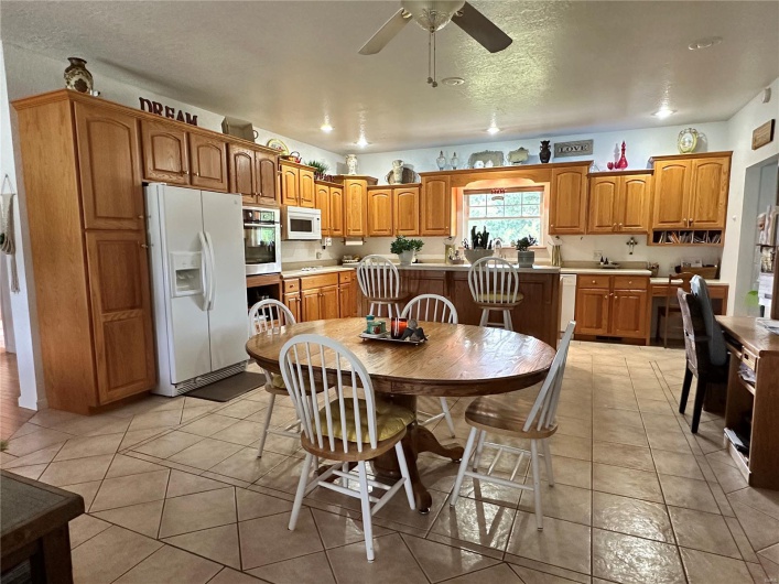 Kitchen featuring light countertops, a ceiling fan, brown cabinetry, and white appliances
