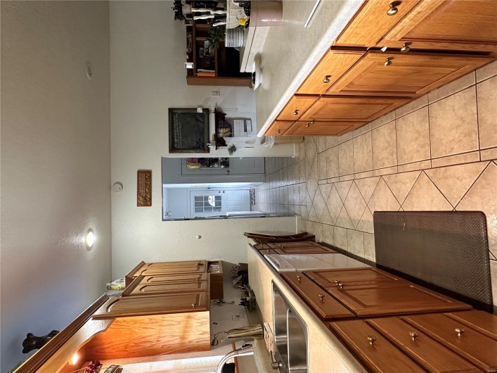 Kitchen with light countertops, a sink, dishwashing machine, and light tile patterned floors