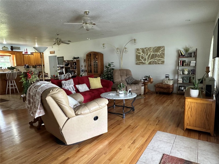 Living area with a textured ceiling, ceiling fan, hardwood floors, and arched walkways