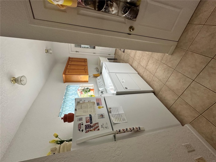 Washroom featuring a textured wall, cabinet space, separate washer and dryer, and light tile patterned floors