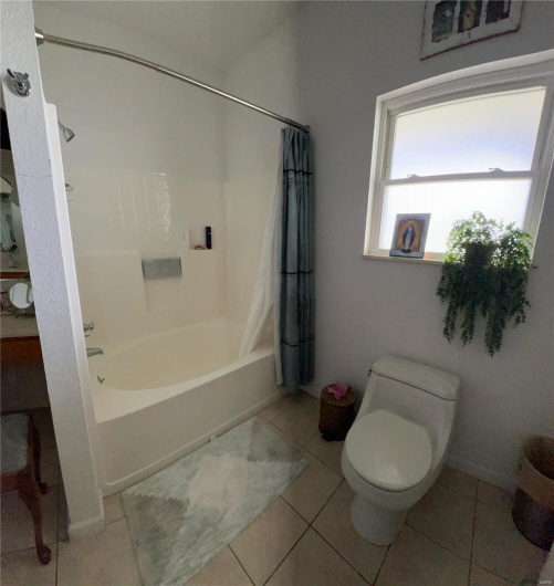 Full bath with baseboards, shower / tub combo with curtain, toilet, and tile patterned flooring