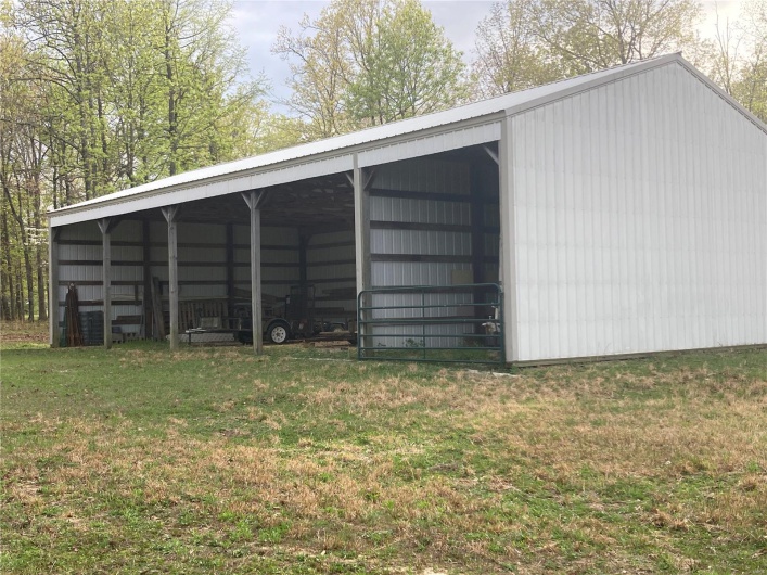 View of pole building with a carport and a lawn