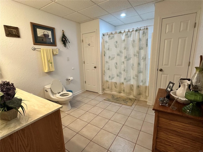 Bathroom featuring tile flooring, vanity, toilet, shower / bath combination with curtain, and a paneled ceiling