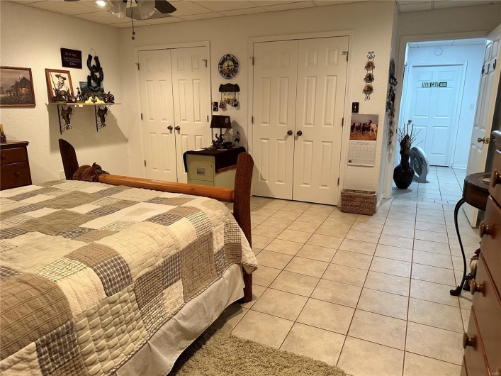 Bedroom with closet, ceiling fan, light tile  floors, and a drop ceiling