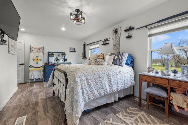 Bedroom with visible vents, baseboards, multiple windows, and wood finished floors