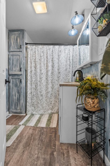 Full bath featuring a shower with shower curtain, wood finished floors, and a sink
