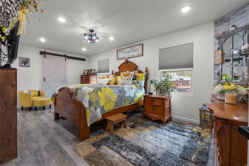 Bedroom featuring recessed lighting, baseboards, a barn door, and wood finished floors