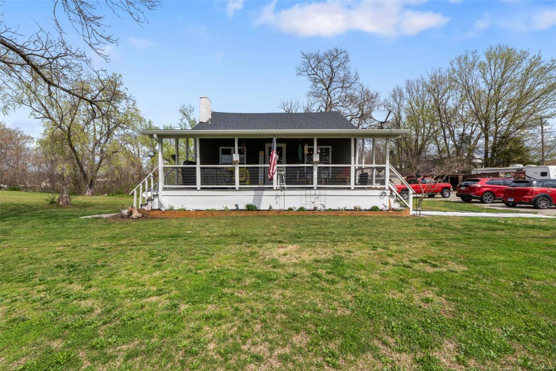 View of front facade featuring a chimney, a front yard, and covered porch