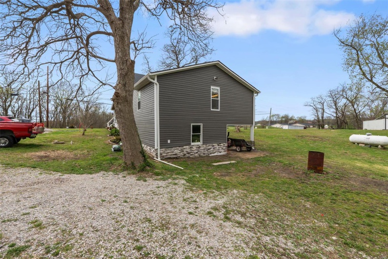 View of side of home featuring a lawn and stone siding