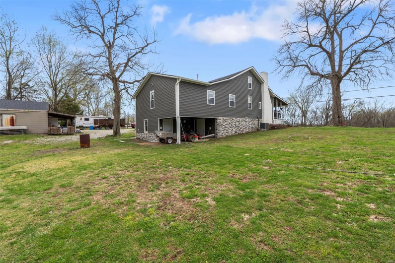 Rear view of property featuring central AC unit, a yard, and a chimney