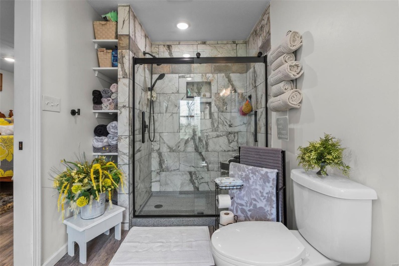 Bathroom featuring a stall shower, wood finished floors, and toilet