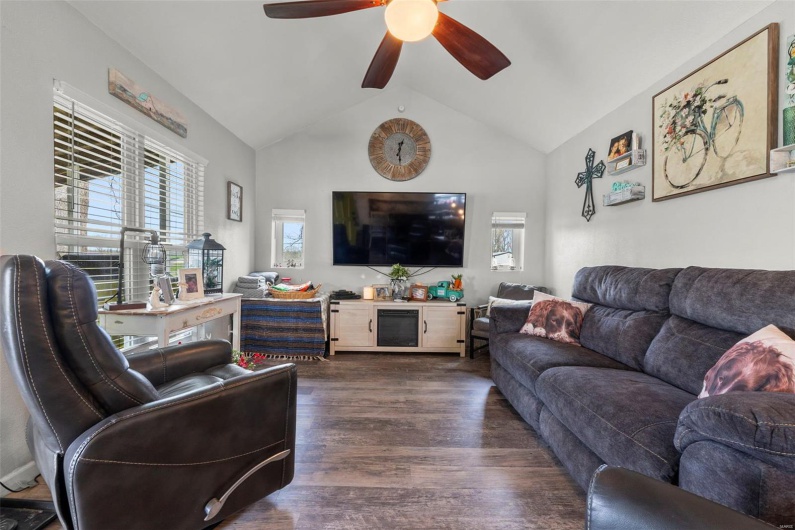 Living room featuring dark wood-style floors, lofted ceiling, and ceiling fan