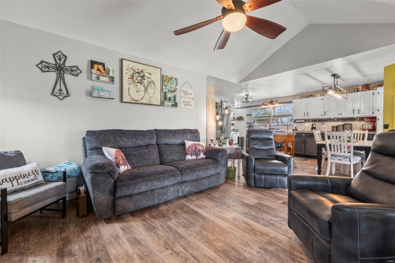 Living room featuring wood finished floors, vaulted ceiling, and ceiling fan