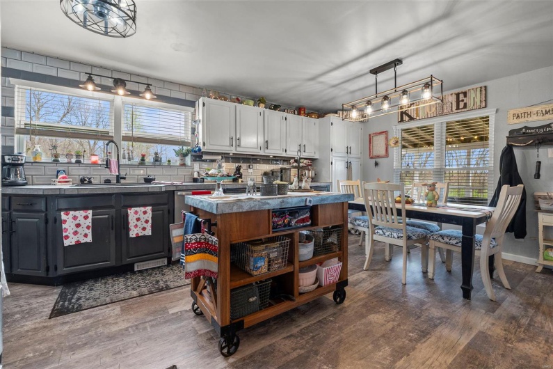 Kitchen featuring open shelves, a center island, backsplash, a sink, and wood finished floors