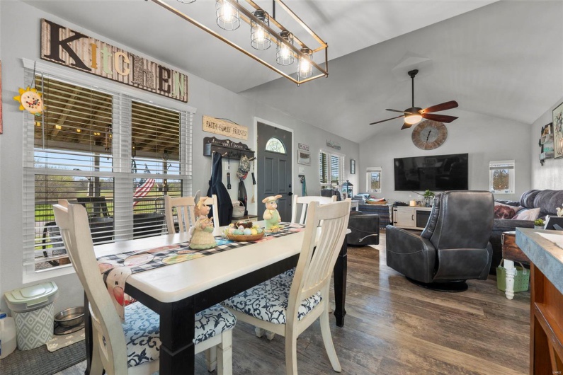 Dining area with ceiling fan with notable chandelier, lofted ceiling, and dark wood-style flooring