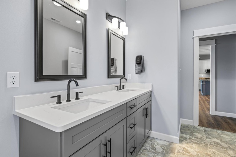 Bathroom with baseboards, double vanity, visible vents, and a sink