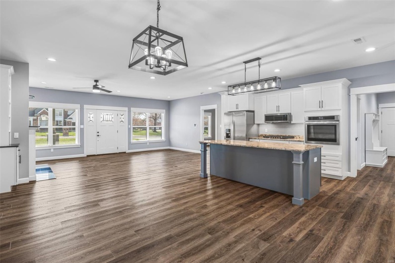 Kitchen featuring open floor plan, a kitchen bar, dark wood finished floors, white cabinets, and appliances with stainless steel finishes