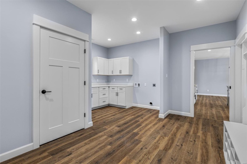 Clothes washing area with dark wood-style floors, hookup for a washing machine, and electric dryer hookup