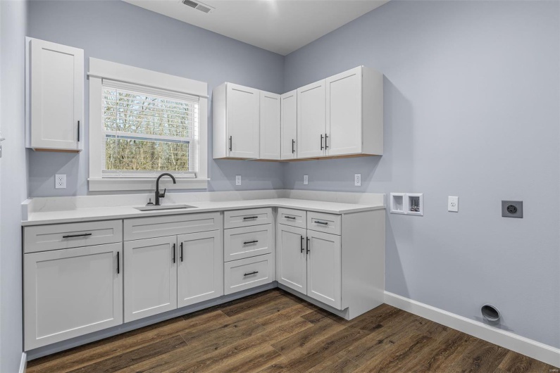Kitchen with white cabinets, light countertops, a sink, and baseboards