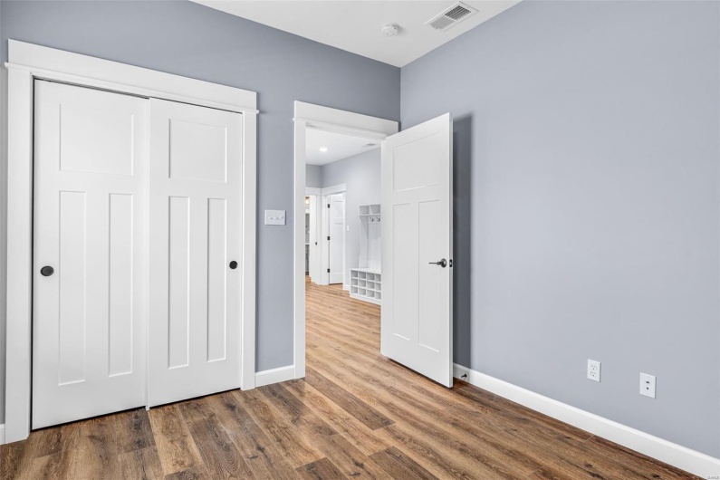 Unfurnished bedroom with wood finished floors, a closet, baseboards, and visible vents