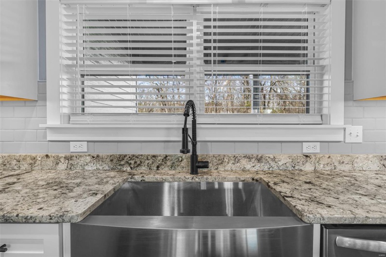 Interior details featuring a sink, light stone counters, and decorative backsplash